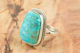 Genuine High Grade Kingman Web Turquoise set in Sterling Silver Ring. Created by Navajo Artist Larson Lee. Signed by the artist. The Mineral Park Mine, in the Cerbat Mountains 14 miles northwest of Kingman, was first mined by Indians centuries before white man came to the area. It is one of the three sites of prehistoric mining localities in the state of Arizona. Mineral Park was the most extensively worked area by the Indians of the three. S.A. �Chuck� Colbaugh found a cache of stone hammers uncovered in ancient trenches and tunnels, when he had the turquoise mining concession in May of 1962. Ithaca Peak and Turquoise Mine (formally called Aztec Mountain or Aztec Peak) are the most famous of the peaks in the area containing turquoise.